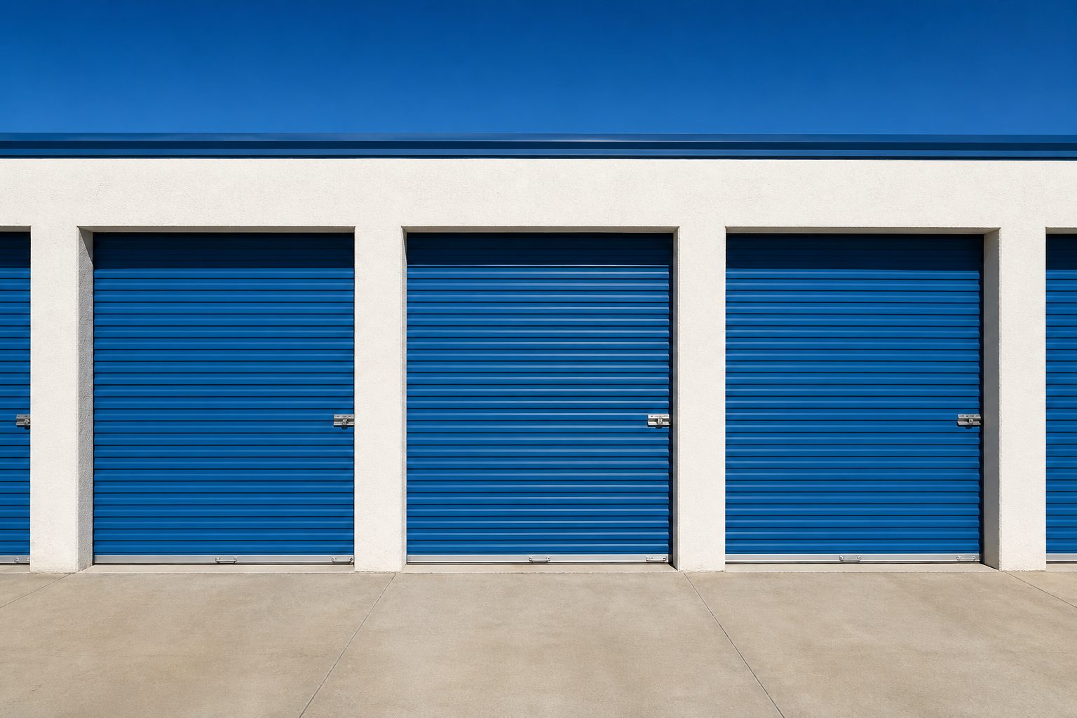 A row of blue roll-up storage doors in bright New Mexico sun